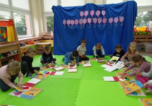 Dzieci na dywanie korzystające z książek.